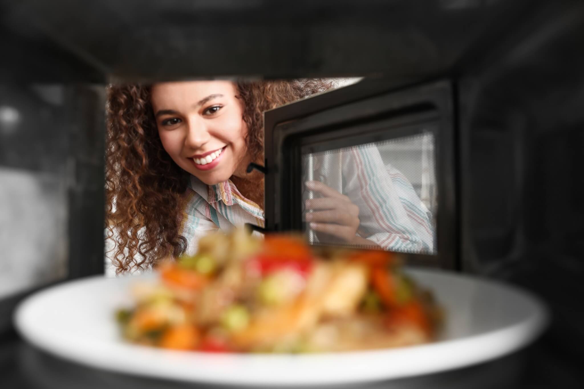A woman looking into a microwave