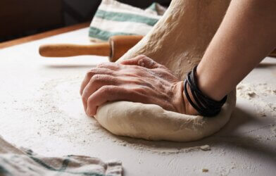 Someone kneading pizza dough