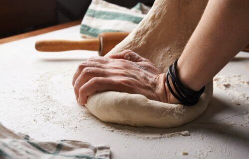 Someone kneading pizza dough