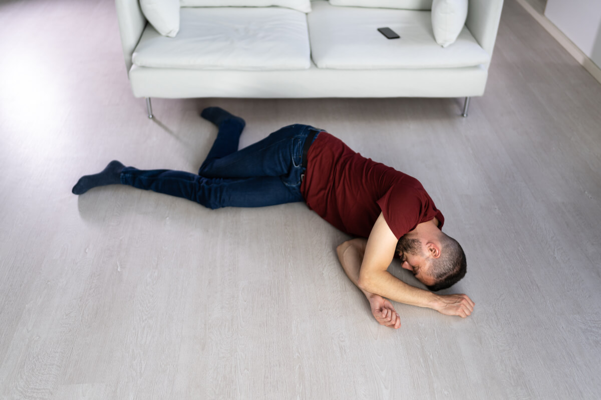 Unconscious Young Man Lying On Floor In Living Room