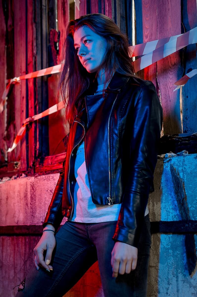 Woman leaning against wall in leather jacket