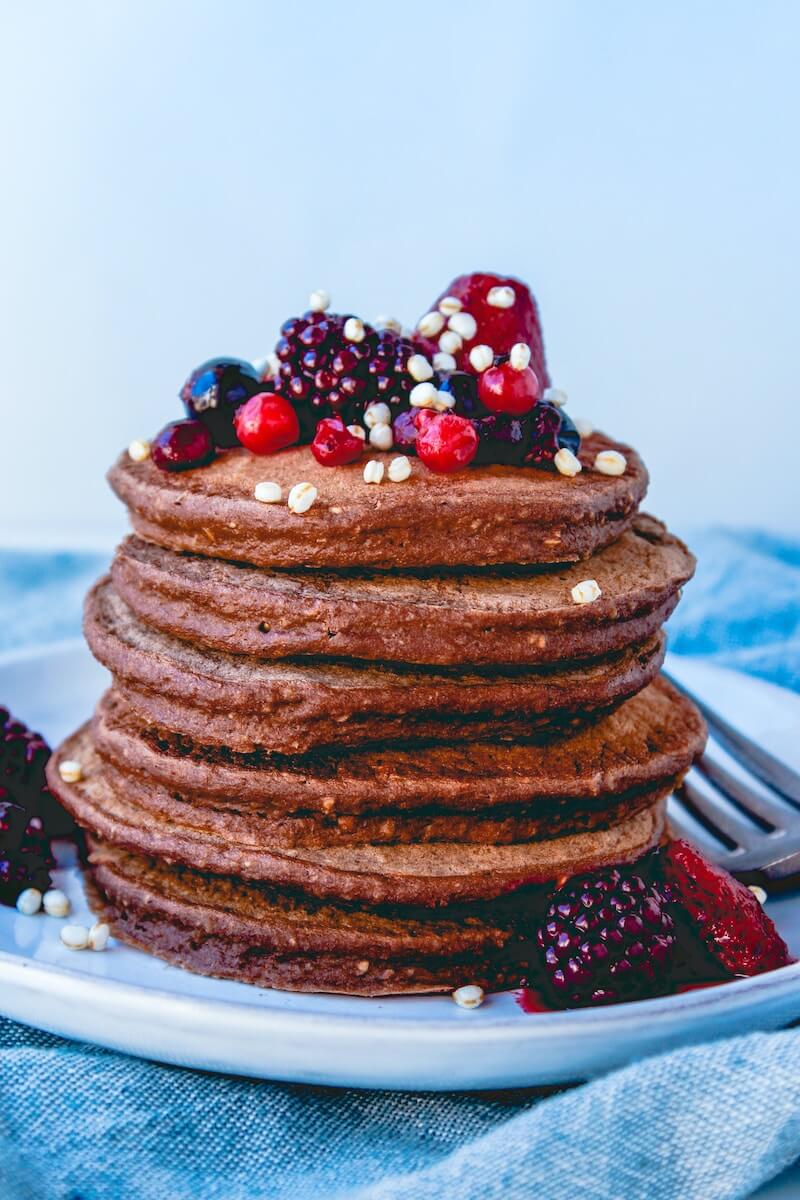 a stack of chocolate pancakes with berries on top