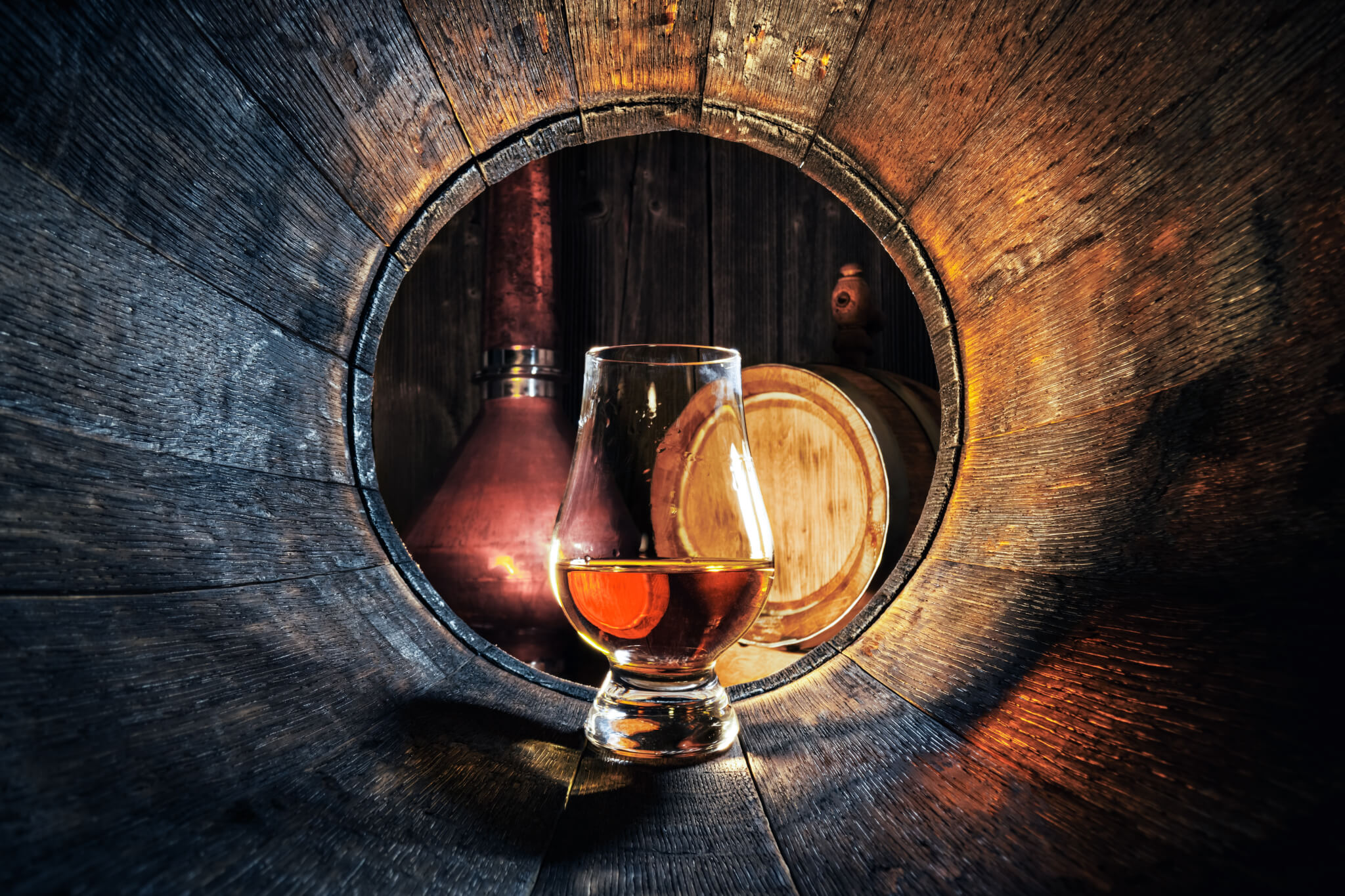 A glass of whiskey in a distillery barrel