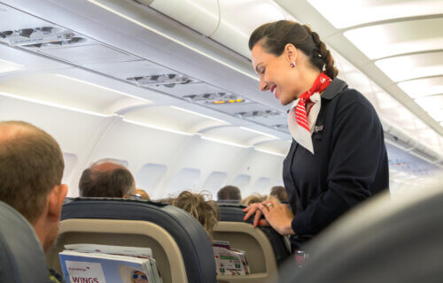 A female flight attendant is speaking with a passenger sitting in the economy class on Eurowings Airline.