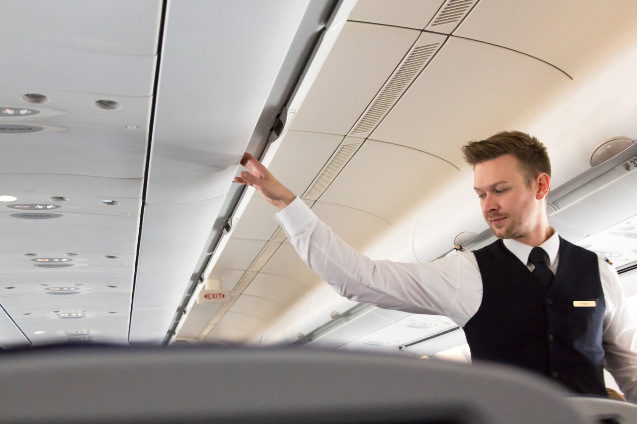 Flight attendant checking overhead compartments on airplane