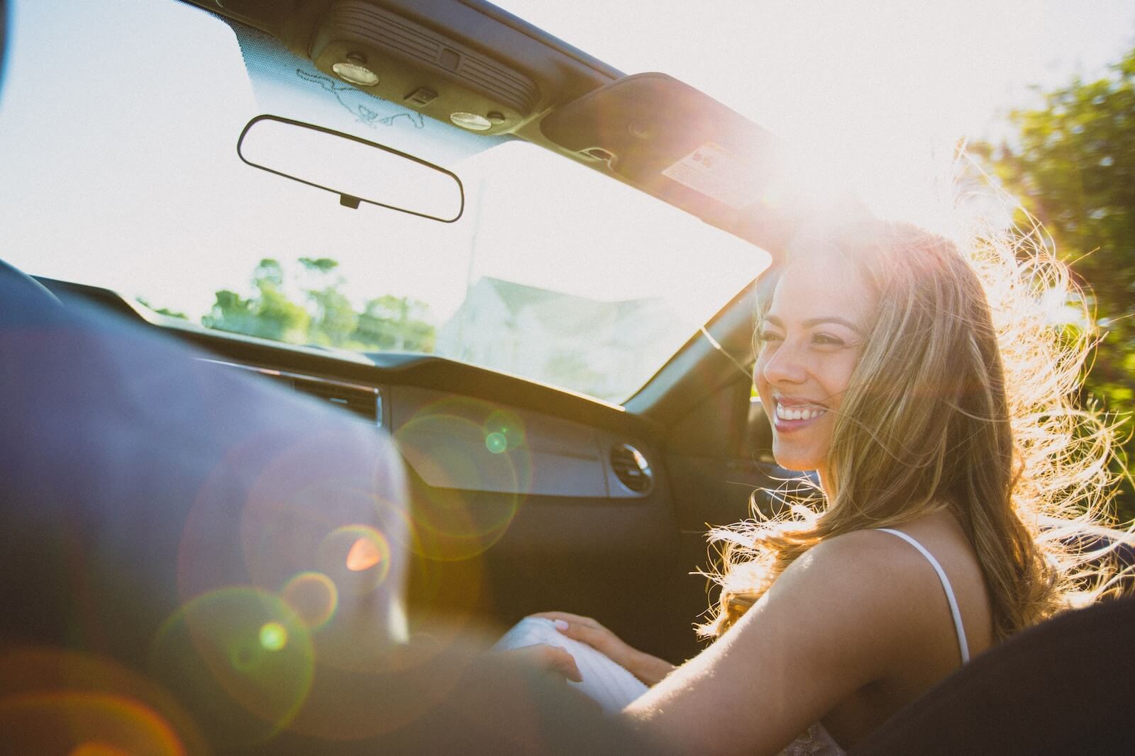 Smiling woman sitting inside a convertible car