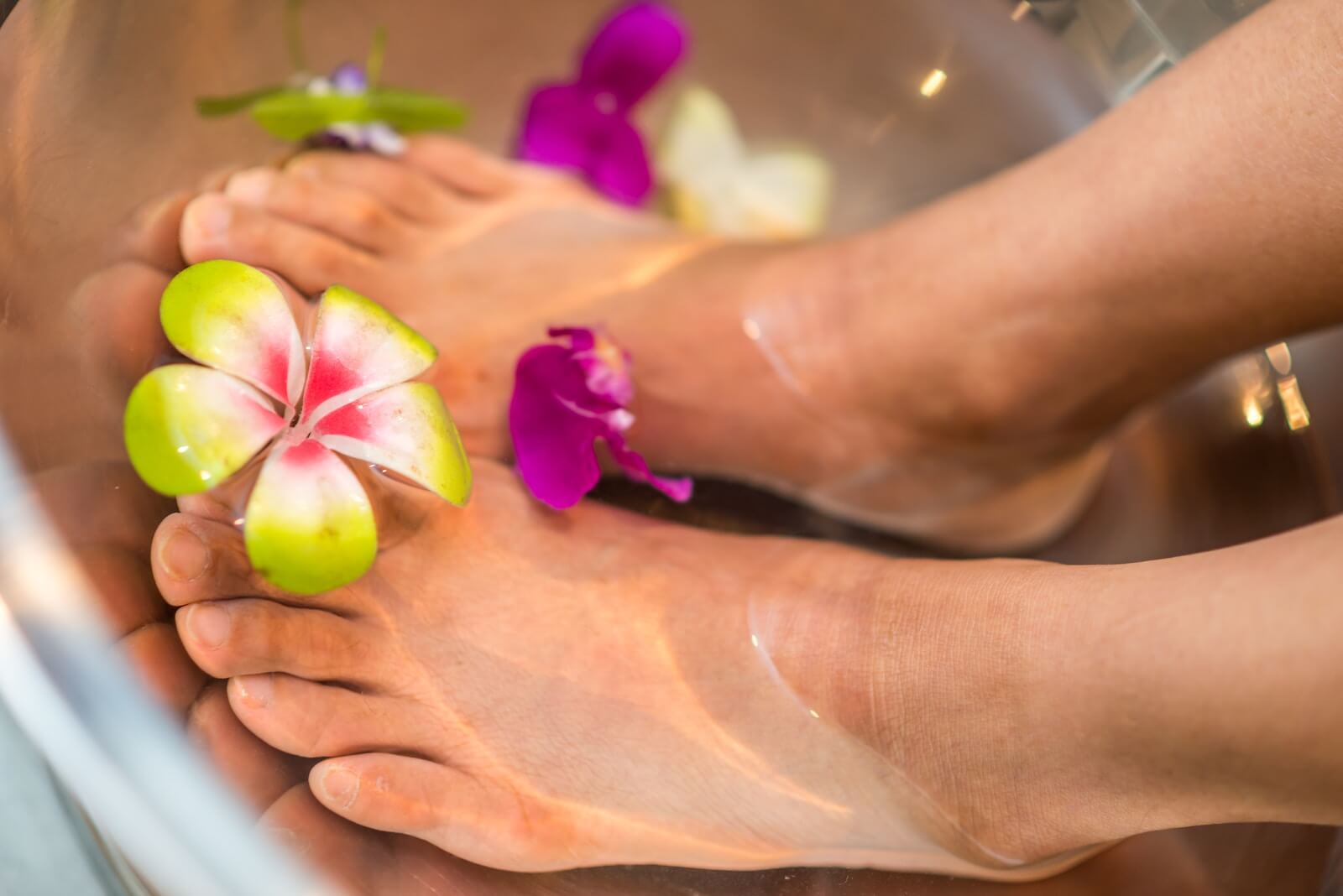 A person soaking in a foot bath with flowers