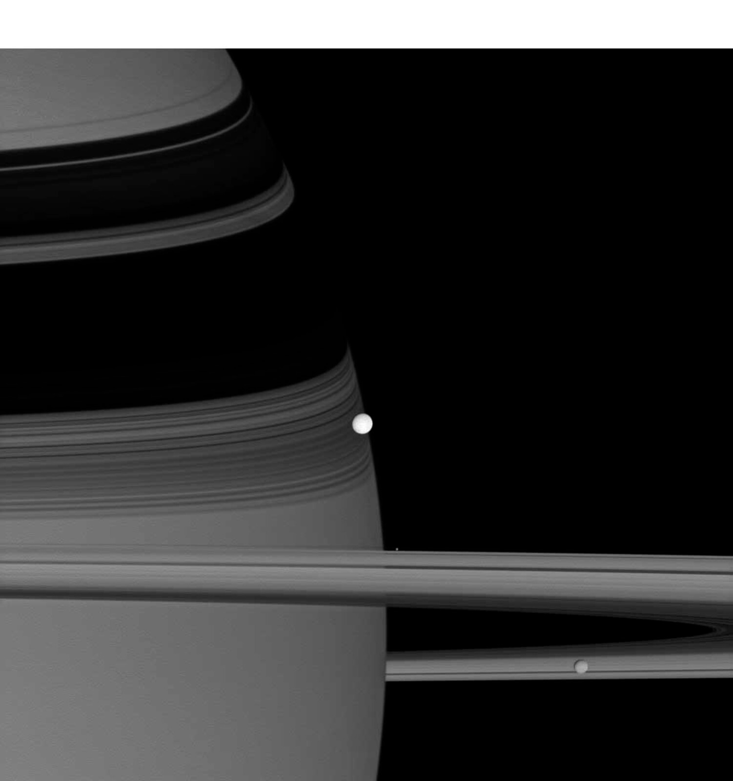NASA’s Cassini spacecraft captured this image of reflective Enceladus, seen at center, as it orbits Saturn