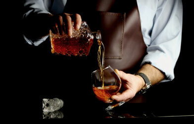 A bartender pouring brandy into a glass