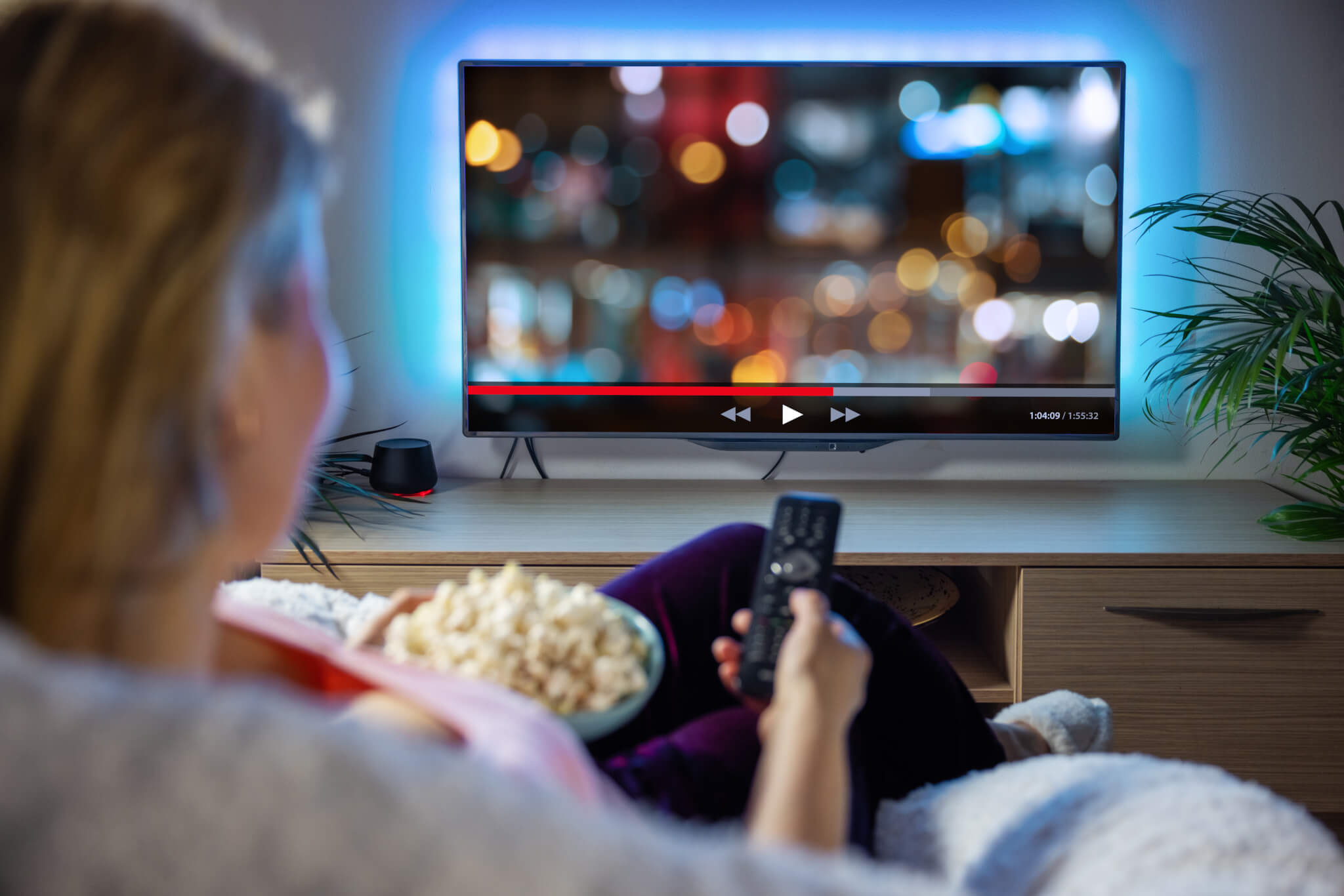 A woman watching TV with a bowl of popcorn