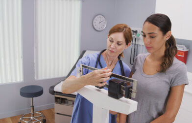nurse weighing female patient
