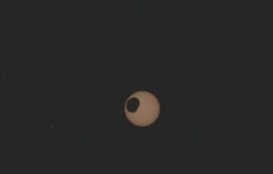 The potato-shaped Mars moon of Phobos transits from top to bottom left across the Sun