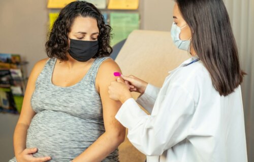 a pregnant woman wearing a face mask is being examined by a doctor