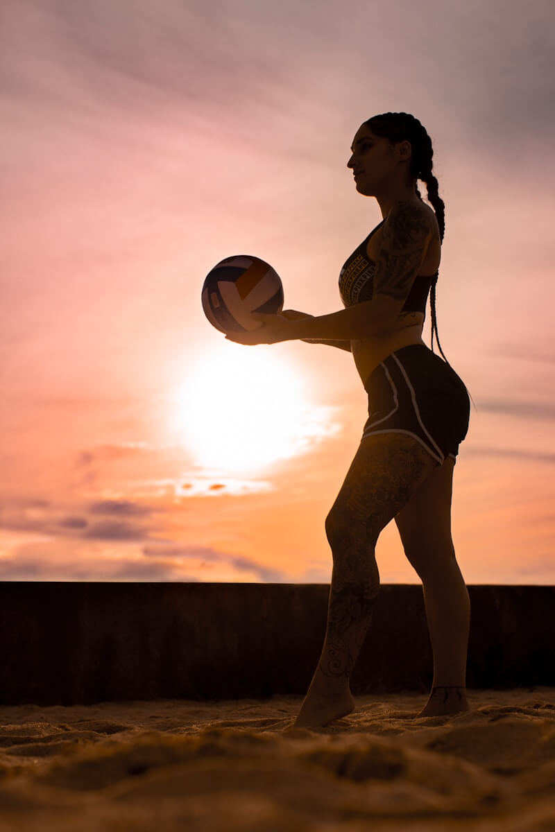 woman in white bikini holding yellow ball during sunset