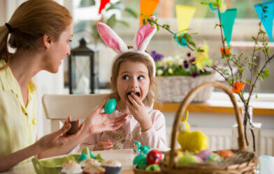 Mother and daughter celebrating Easter, eating chocolate eggs.