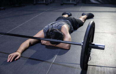 Unconscious Athlete on the Gym Floor with a Barbell in Front of Him