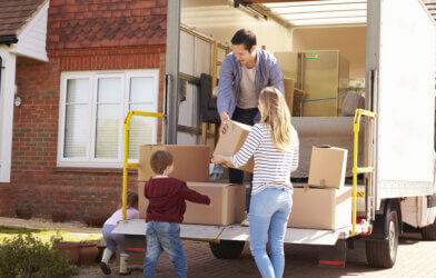 Family Unpacking Moving In Boxes From Removal Truck