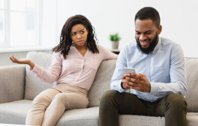 Phubbing. Angry woman looking at her boyfriend stuck in smartphone