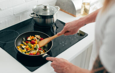 Person cooking vegetables in frying pan