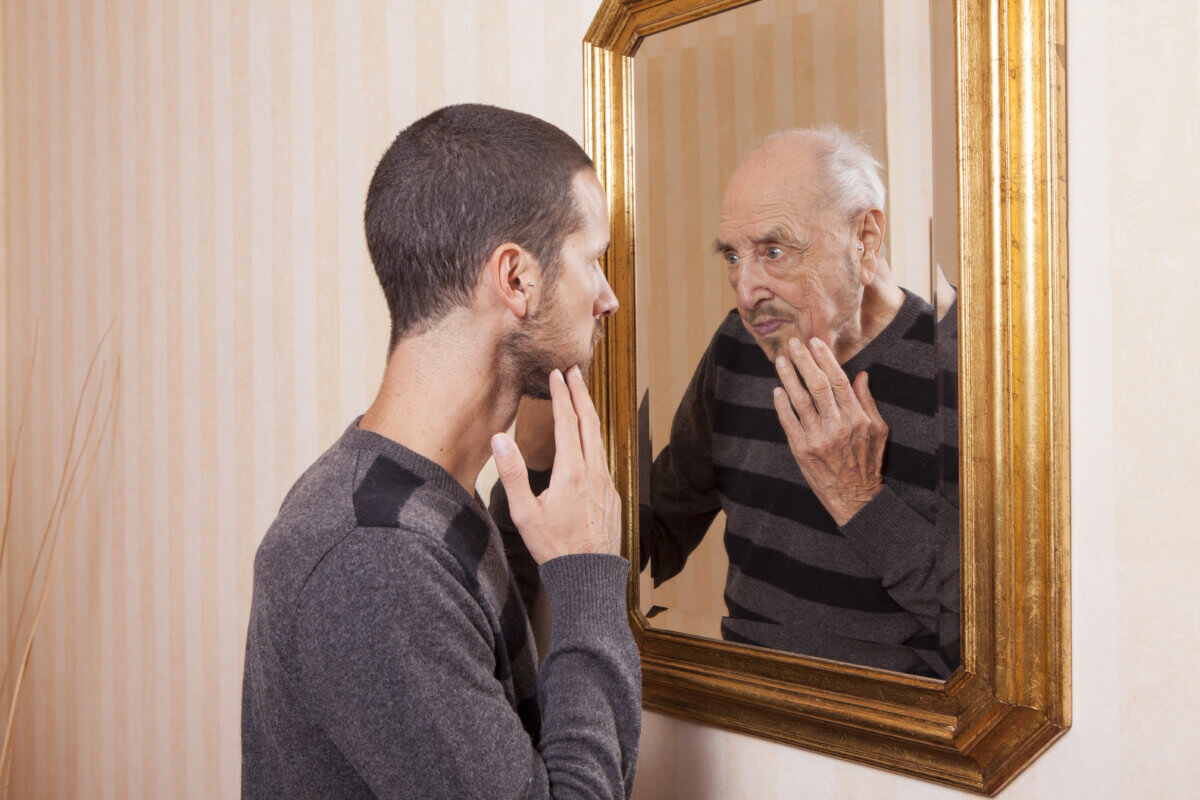 young man looking at his older self in the mirror