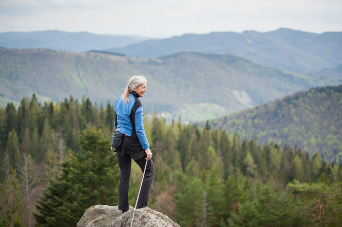 Climbing woman standing on the top of the cliff