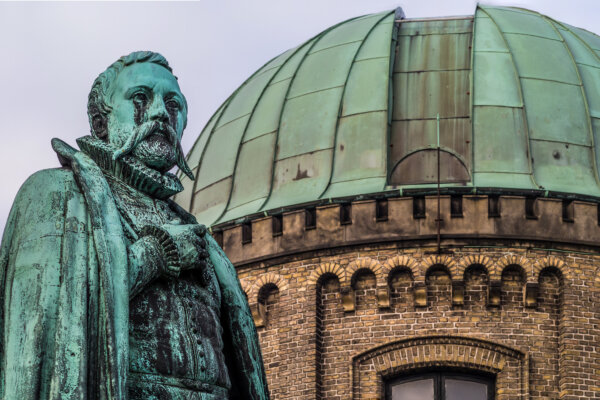 Statue of Tycho brahe in front of a green copper roofed observatory next to Rosenborg castle in Copenhagen, Denmark
