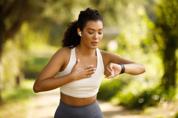 Woman running and checking her heart rate on her fitness tracker